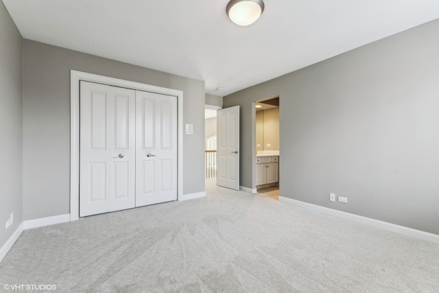 unfurnished bedroom featuring light carpet, ensuite bathroom, and a closet