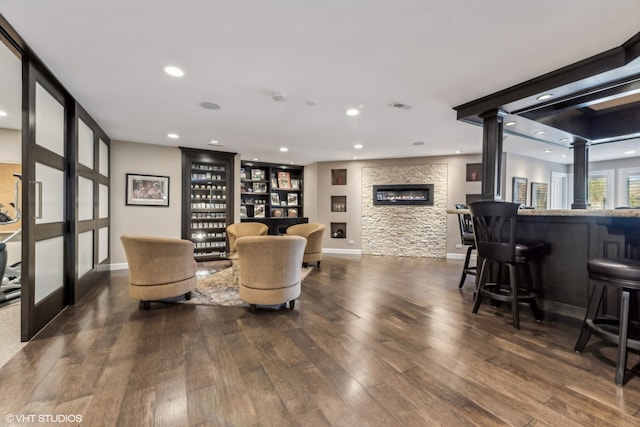 living room with dark hardwood / wood-style flooring, ornate columns, and bar area