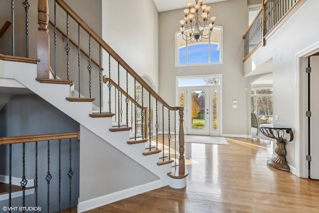 entryway with a towering ceiling, a chandelier, and hardwood / wood-style flooring