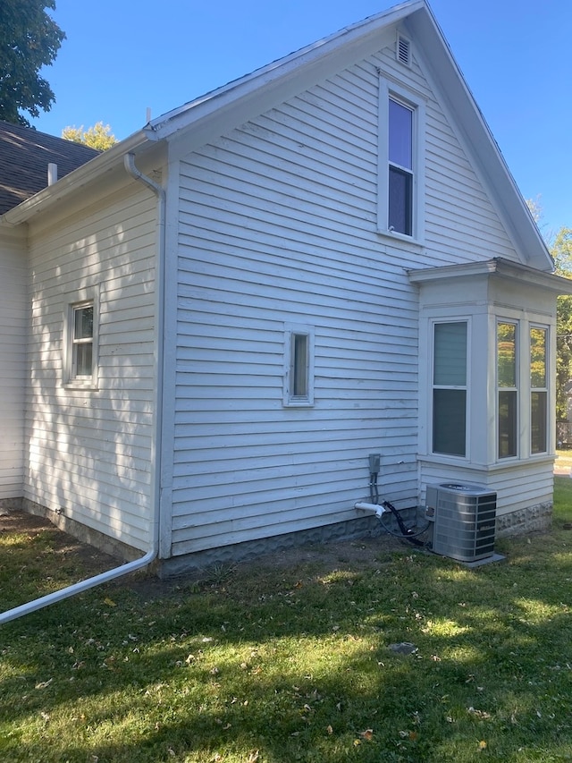 view of side of property with central AC unit and a lawn