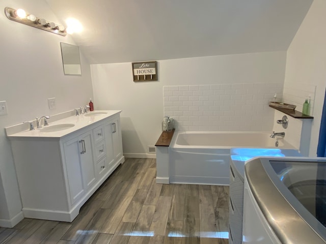 bathroom featuring a bathing tub, hardwood / wood-style floors, vanity, and washer / clothes dryer