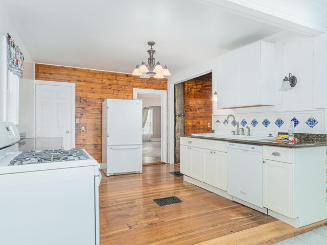 unfurnished living room with lofted ceiling, wooden walls, light hardwood / wood-style flooring, and an inviting chandelier