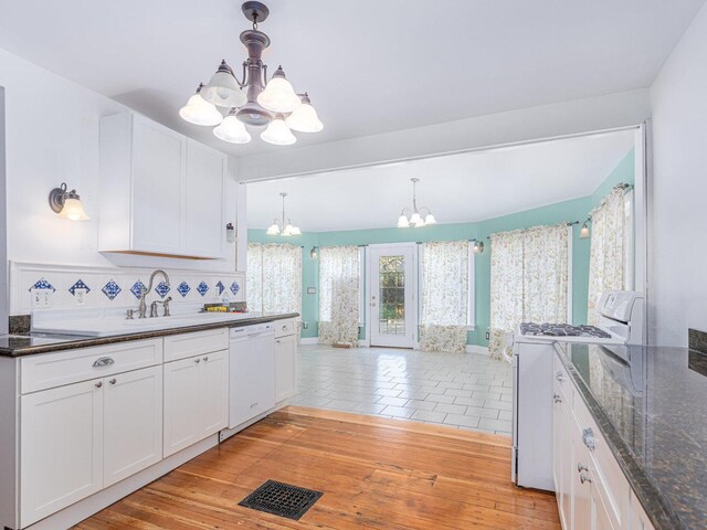 kitchen with light hardwood / wood-style floors, white cabinets, wooden walls, and white appliances