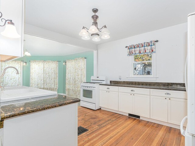 kitchen featuring white appliances, light wood-type flooring, white cabinetry, wooden walls, and decorative backsplash