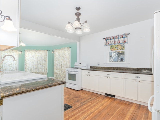 kitchen featuring white appliances, light wood-type flooring, pendant lighting, and white cabinets