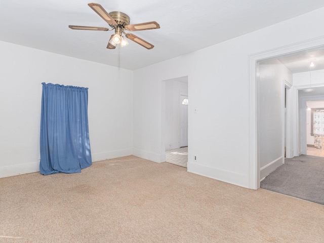 empty room featuring ceiling fan, baseboards, and light colored carpet