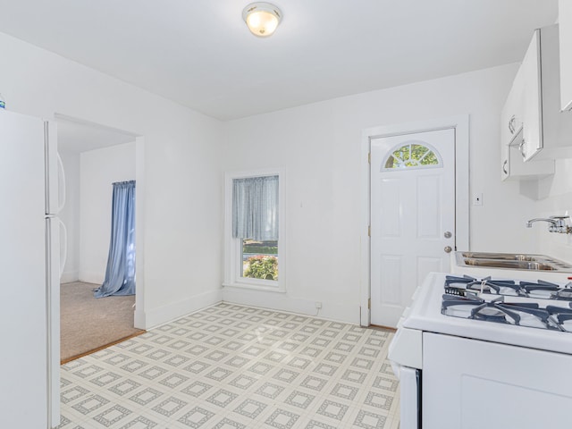 kitchen featuring sink, white cabinetry, light colored carpet, and white appliances