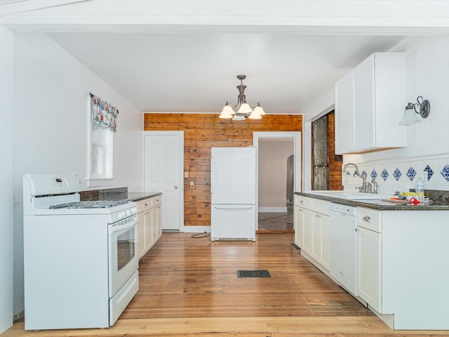 kitchen with white appliances, dark countertops, light wood-type flooring, white cabinetry, and a sink