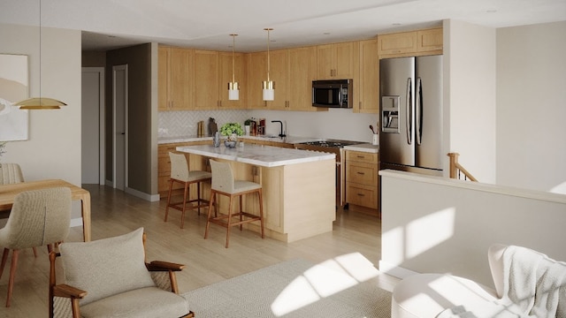 kitchen featuring a kitchen bar, stainless steel fridge, stove, a center island with sink, and hanging light fixtures