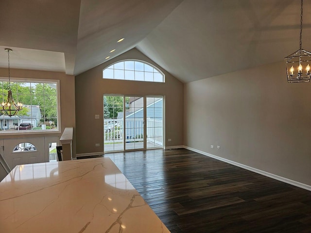 unfurnished living room featuring a chandelier, a towering ceiling, and dark hardwood / wood-style flooring