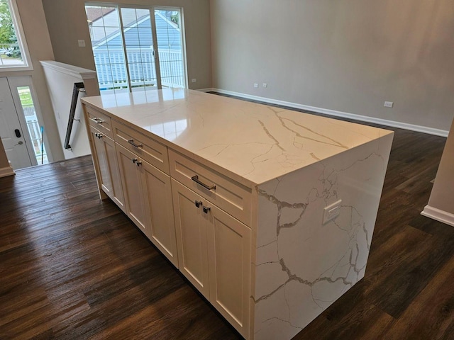 kitchen with a center island, light stone countertops, and dark wood-type flooring