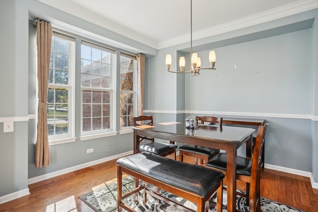 dining space featuring ornamental molding, hardwood / wood-style floors, and an inviting chandelier