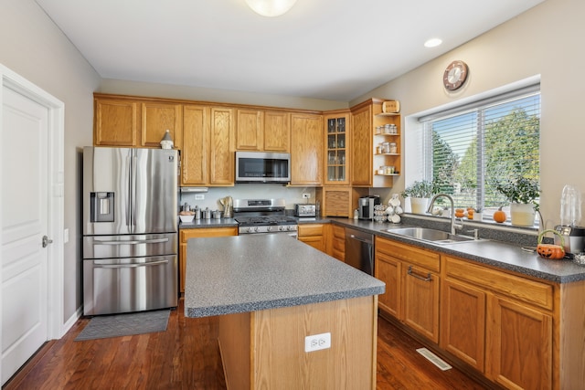 kitchen featuring sink, a kitchen island, appliances with stainless steel finishes, and dark hardwood / wood-style flooring