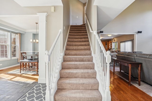 stairs with a chandelier, crown molding, wood-type flooring, and a high ceiling