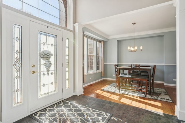 entryway with ornamental molding, a chandelier, ornate columns, and dark hardwood / wood-style flooring