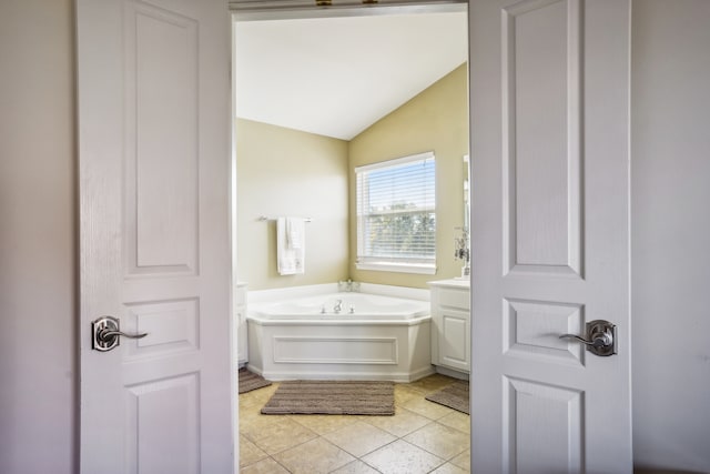 bathroom featuring tile patterned floors, vaulted ceiling, and a bath