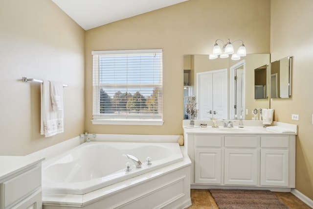 bathroom featuring vanity, a tub to relax in, and vaulted ceiling