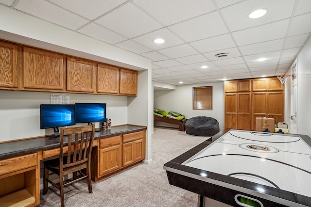 game room with built in desk, a paneled ceiling, and light colored carpet