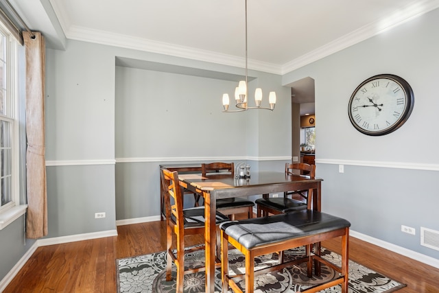 dining room with hardwood / wood-style flooring, ornamental molding, and an inviting chandelier