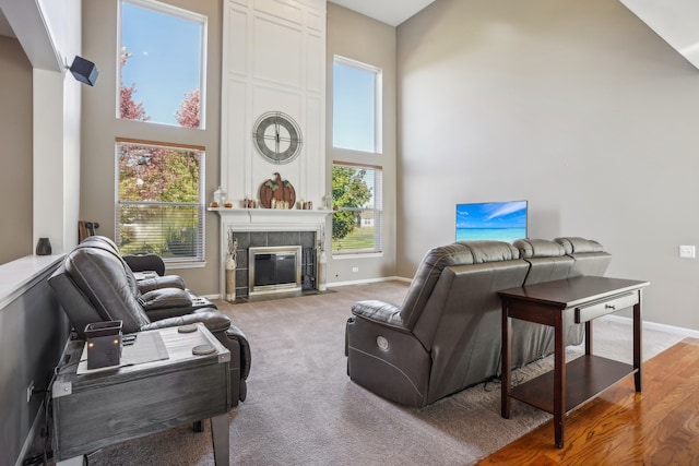 living room with a high ceiling, carpet flooring, and a tile fireplace