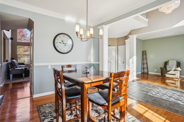 dining room featuring dark wood-type flooring, crown molding, decorative columns, and a chandelier