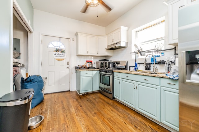 kitchen featuring hardwood / wood-style flooring, backsplash, white cabinetry, appliances with stainless steel finishes, and ceiling fan