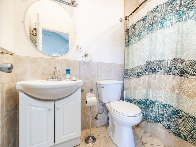 bathroom with tile patterned floors, toilet, vanity, tile walls, and walk in shower