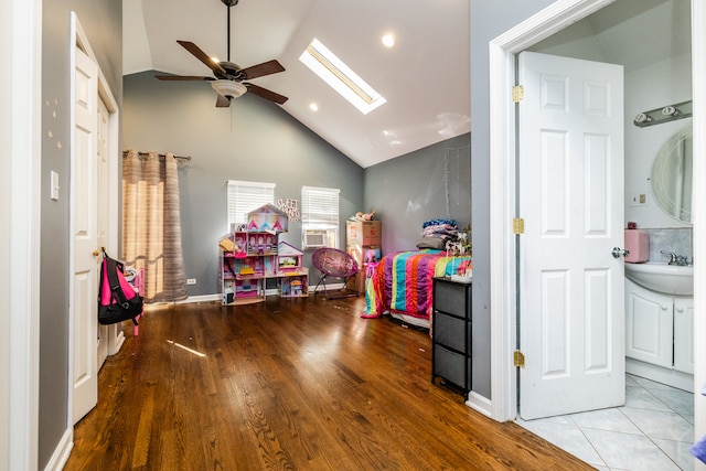 playroom featuring sink, lofted ceiling with skylight, light hardwood / wood-style flooring, and ceiling fan