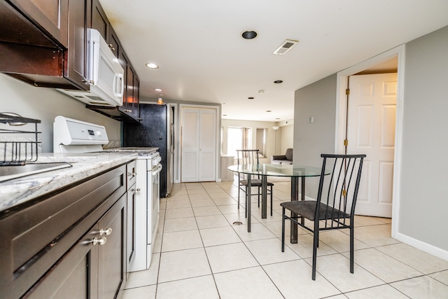 kitchen with white appliances, light stone countertops, dark brown cabinetry, and light tile patterned floors