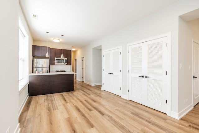 kitchen featuring appliances with stainless steel finishes, light hardwood / wood-style flooring, dark brown cabinets, and kitchen peninsula