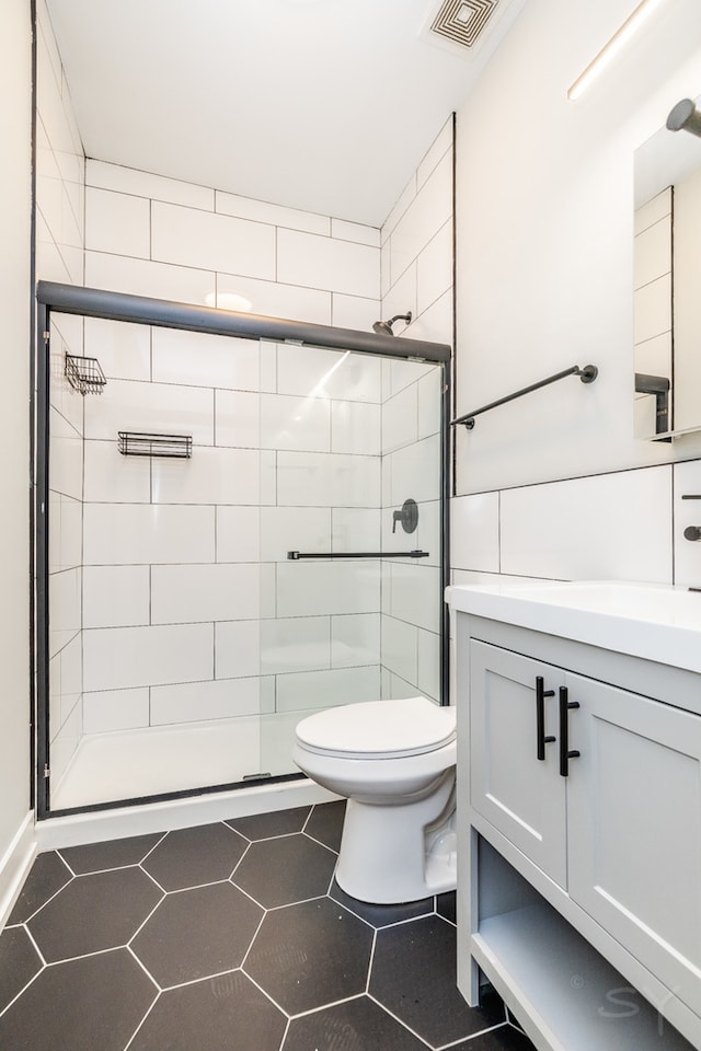 bathroom featuring vanity, toilet, tile patterned floors, and a shower with door