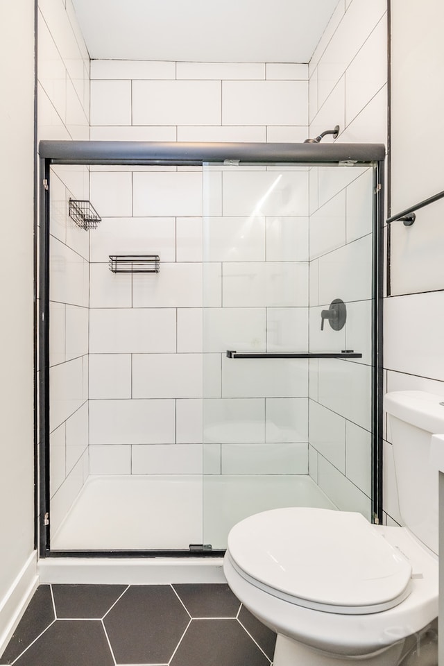 bathroom with a shower with shower door, toilet, and tile patterned flooring