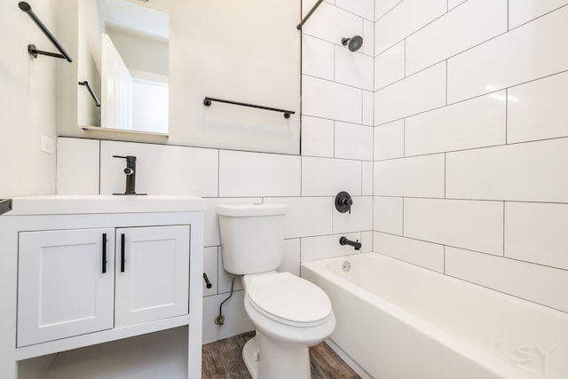 full bathroom featuring hardwood / wood-style flooring, toilet, tiled shower / bath, vanity, and tile walls