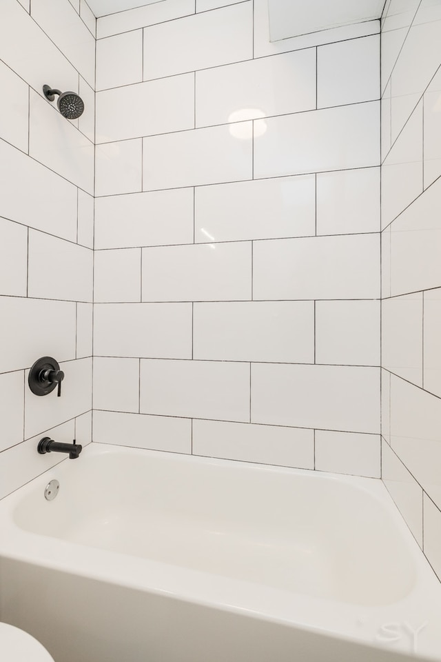 bathroom with toilet and tiled shower / bath