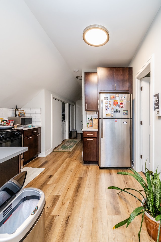 kitchen with light hardwood / wood-style flooring, dark brown cabinetry, backsplash, and stainless steel refrigerator