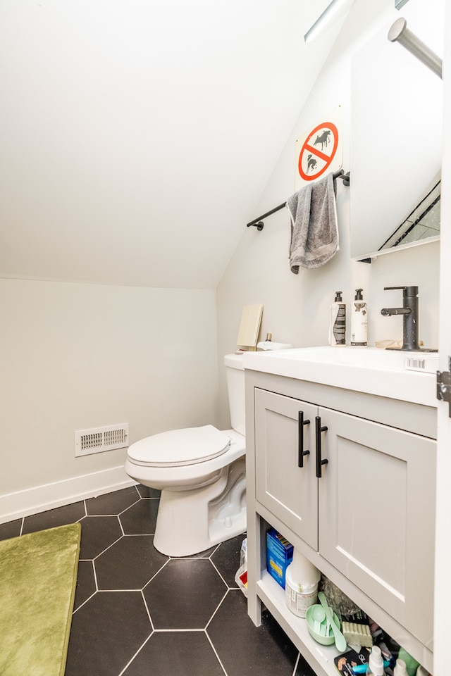 bathroom featuring vanity, toilet, lofted ceiling, and tile patterned flooring