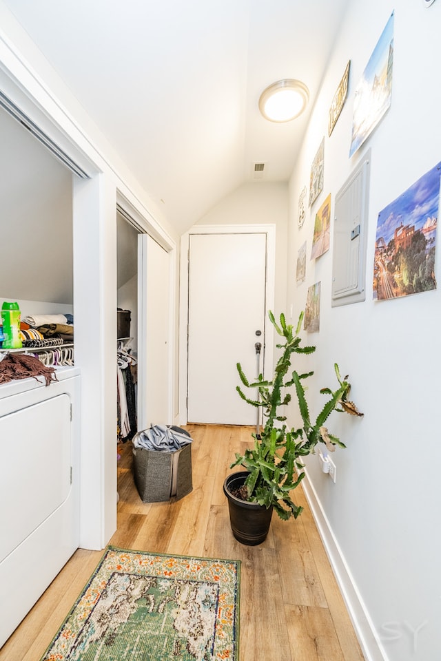 corridor with lofted ceiling, washer / clothes dryer, electric panel, and hardwood / wood-style floors