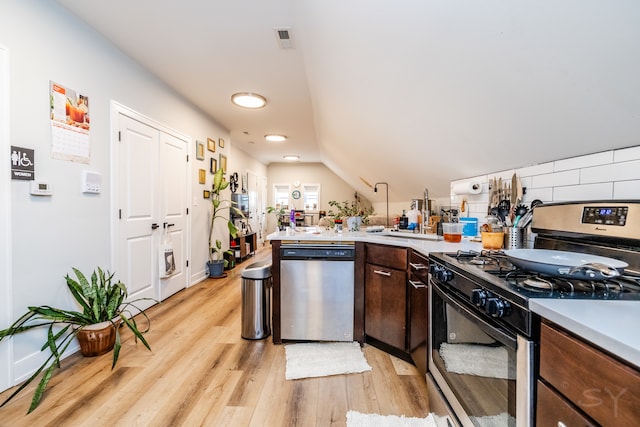 kitchen featuring lofted ceiling, dishwasher, dark brown cabinetry, light wood-type flooring, and gas range oven