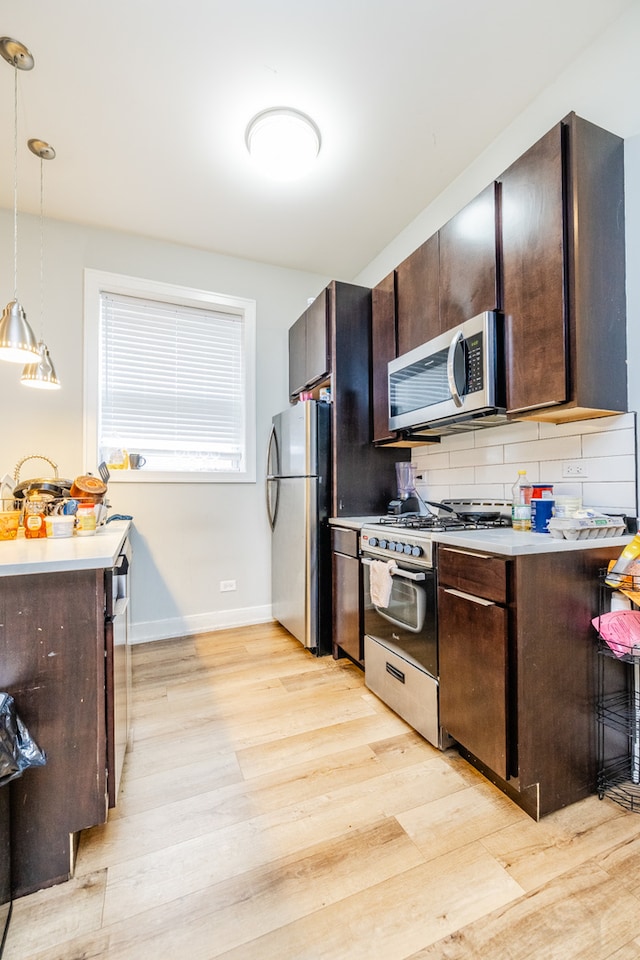 kitchen with stainless steel appliances, dark brown cabinets, light hardwood / wood-style flooring, and hanging light fixtures