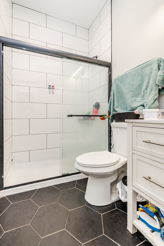 bathroom with vanity, toilet, walk in shower, and tile patterned flooring