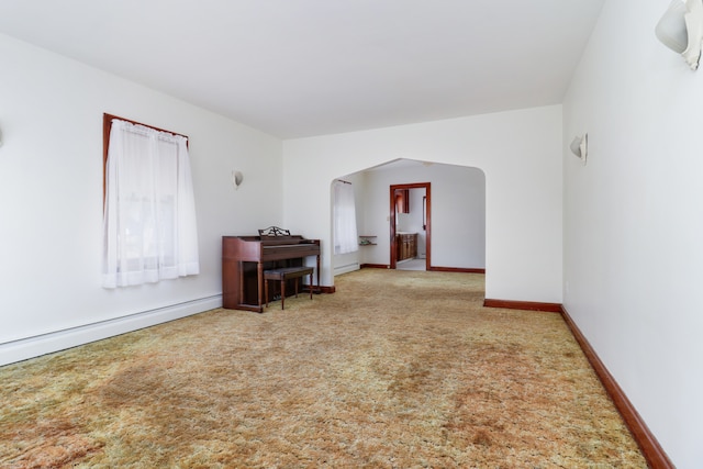 carpeted empty room featuring a baseboard heating unit