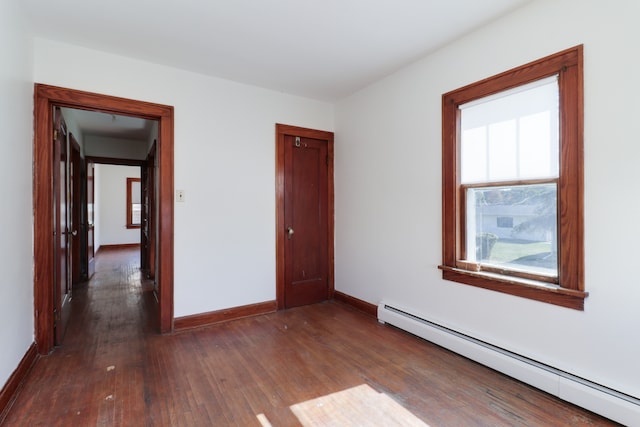 spare room with dark wood-type flooring and a baseboard radiator