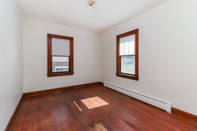 unfurnished room featuring dark wood-type flooring and a baseboard heating unit