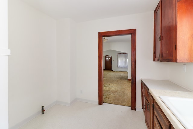 corridor with sink, vaulted ceiling, and light colored carpet