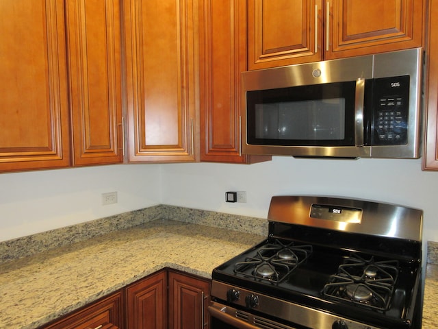 kitchen with black gas range and light stone countertops