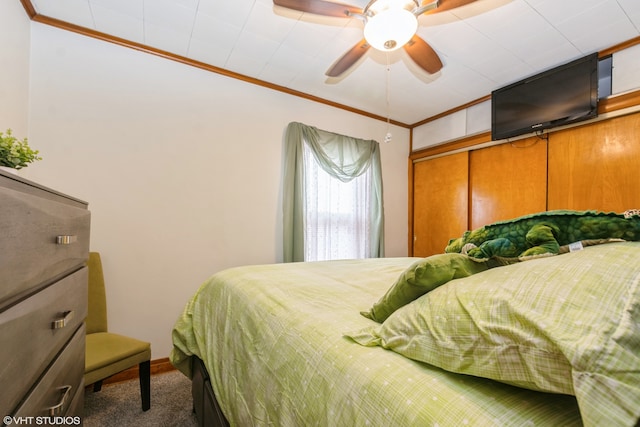 carpeted bedroom with a closet, ornamental molding, and ceiling fan