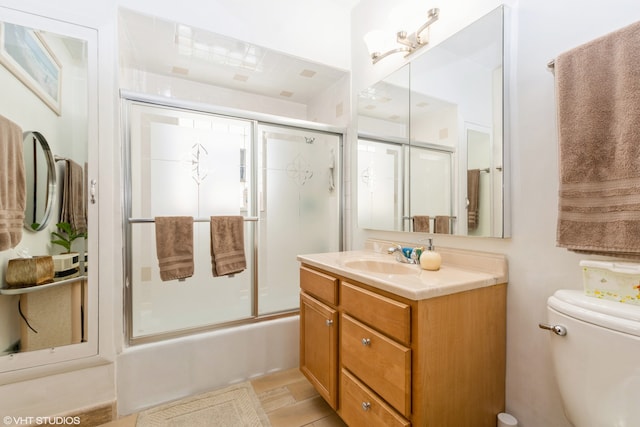 full bathroom featuring vanity, toilet, and shower / bath combination with glass door