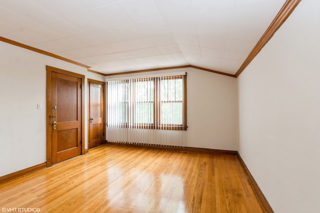 spare room featuring light hardwood / wood-style flooring, ornamental molding, and lofted ceiling