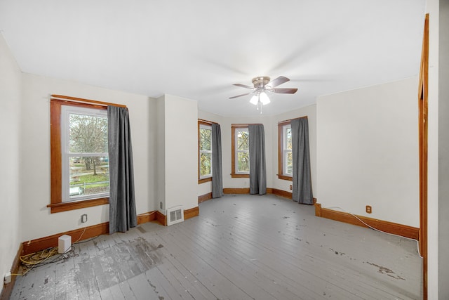 empty room with light hardwood / wood-style floors, ceiling fan, and a healthy amount of sunlight