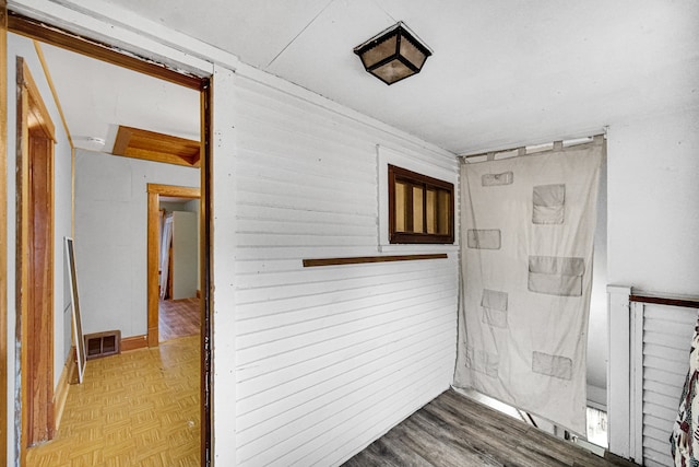 corridor with wooden walls and light parquet flooring